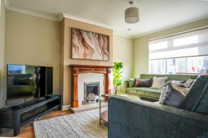 een woonkamer met een bank en een open haard bij 4 BDR House At Caledonia Luxe Stays Short Lets & Serviced Accommodation Bo'ness in Boʼness