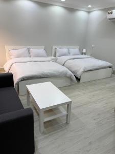 a white room with two beds and a coffee table at the farm break in Madīnat Zāyid