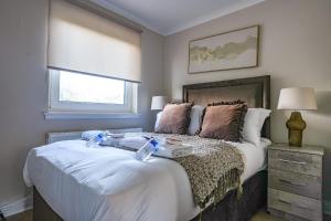 een slaapkamer met een bed met witte lakens en een raam bij 4 BDR House At Caledonia Luxe Stays Short Lets & Serviced Accommodation Bo'ness in Boʼness