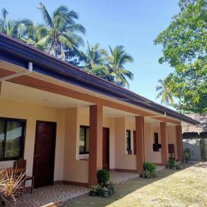 a small house with palm trees in the background at Two Season Tourist Inn in San Vicente