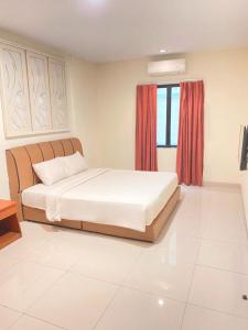 una camera da letto con un grande letto bianco con una finestra di Hotel Beverly Inn Batam Center a Batam Center