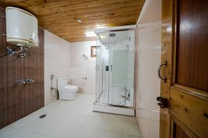 a bathroom with a glass shower and a toilet at Hotel Monal in Manāli +35 photos
