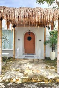 a building with a large wooden door and a thatch roof at Floraison Living Villa Yogyakarta in Ngaglik