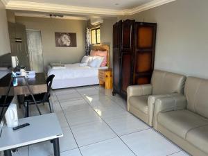 Una sala de estar con una cama, un sofá y una mesa. en La Vue, en Port Shepstone