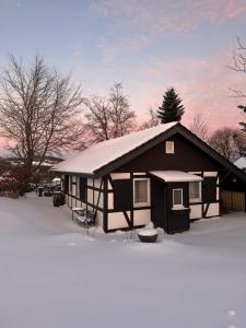 a house with a snow covered roof in the snow at Berghütte Astenpanorama in Winterberg