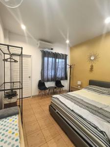 a bedroom with a bed and two chairs and a window at Merit Courtyard Suvarnabhumi House in Lat Krabang