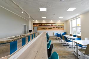 une cafétéria avec des tables et des chaises et un tableau au mur dans l'établissement Haus Klaarstrand, à Wenningstedt
