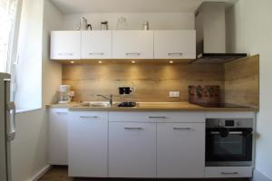 a kitchen with white cabinets and a sink at Gîte Chez Reine à ÉtivalClairefontaine Vosges Cal in Étival-Clairefontaine