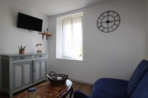 a living room with a couch and a clock on the wall at Gîte Chez Reine à ÉtivalClairefontaine Vosges Cal in Étival-Clairefontaine