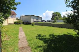 a grassy yard with a fence and a house at Gîte Chez Reine à ÉtivalClairefontaine Vosges Cal in Étival-Clairefontaine