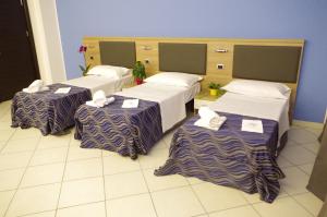 3 camas en una habitación con sábanas moradas y blancas en Hotel V7, en Milán