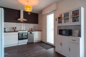 een keuken met witte kasten en een fornuis bij Ty Kordenn - Proche Plage in Sarzeau