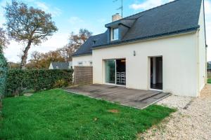 een wit huis met een houten terras in de tuin bij Ty Kordenn - Proche Plage in Sarzeau