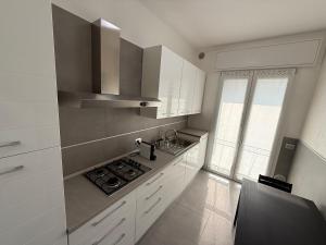 a kitchen with white cabinets and a stove top oven at Appartamenti Rugacesio 24 - B in Pioltello