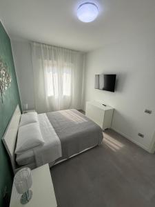 a white bedroom with a bed and a television at Appartamenti Rugacesio 24 - B in Pioltello