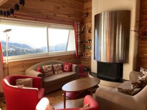 ein Wohnzimmer mit Sofa und Stühlen und einem Kamin in der Unterkunft Appartement esprit montagne in Le Lioran