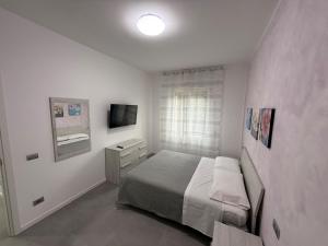 a white bedroom with a bed and a television at Appartamenti Rugacesio 24 - C in Pioltello