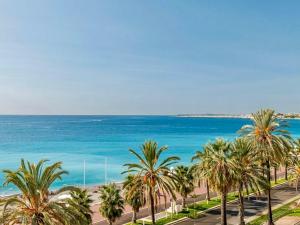 Blick auf einen Strand mit Palmen und das Meer in der Unterkunft Promenade Chic Apartment Sea & City in Nizza
