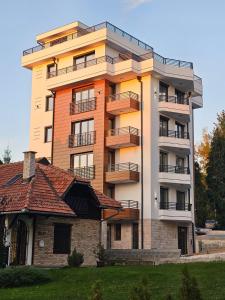 a tall building with a house in front of it at Monte Royal Zlatibor in Zlatibor