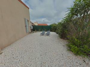 勒卡特海滩Mais 2 pièces 4 couchages PORT LEUCATE NATURISME PL040-040的两把椅子放在建筑物旁边的碎石路上