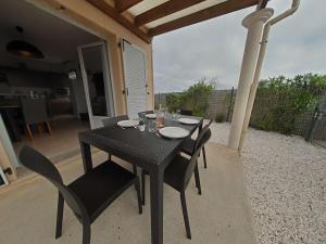 勒卡特海滩Mais 2 pièces 4 couchages PORT LEUCATE NATURISME PL040-040的天井上摆放着黑色的桌椅