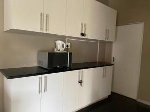 a kitchen with white cabinets and a microwave at Peaceful home in tranquil setting in Durban