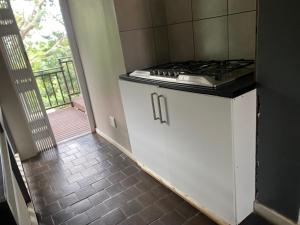 德班Peaceful home in tranquil setting的一间带炉灶的厨房和通往阳台的门