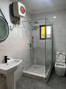 a bathroom with a shower and a sink and a toilet at Hotel Paris Suites in Festac Town