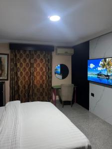 Festac TownにあるHotel Paris Suitesのベッドと薄型テレビのある寝室