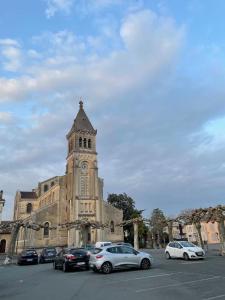 ein Gebäude mit einem Uhrenturm und auf einem Parkplatz geparkten Autos in der Unterkunft Le New Daily, 500m du centre de Dax in Dax
