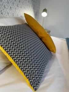 ein Bett mit einem schwarz-gelben Kissen und einer Lampe in der Unterkunft Le New Daily, 500m du centre de Dax in Dax + 6 Fotos