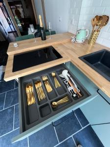 a kitchen counter with a drawer with cooking utensils at Appart' Zen & connect in Ennevelin
