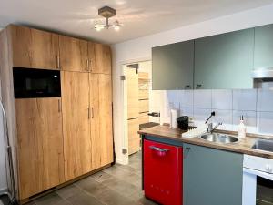 une cuisine avec des placards en bois et un réfrigérateur rouge dans l'établissement Küstenliebe, à Heiligenhafen