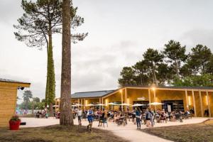 a group of people walking in front of a building at MH310 2 chambres et 2 salles de bain de 40m2 dans camping 4 étoiles in Saint-Julien-en-Born