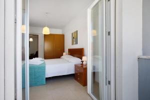 ein Schlafzimmer mit einem Bett und einem Spiegel in der Unterkunft Campo Mar - T1 vista praia in São Martinho do Porto