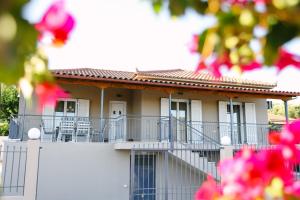 Una casa blanca con balcón y flores rosas. en EftychiaHouse, en Pyrgos