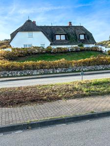 a house with a thatched roof on the side of a road at Wattblick Haus Wattblick "Wattglück" in Rantum +7 photos