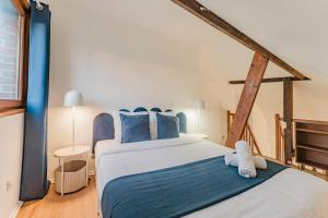ein Schlafzimmer mit einem großen Bett und blauen Kissen in der Unterkunft Appartement 1 chambre mezzanine centre de Roubaix in Roubaix