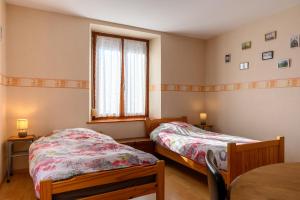 Un dormitorio con dos camas y una ventana. en Le Gîte À Mamie, en Orbey