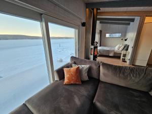 a living room with a couch and a large window at Aurora Jukkas Riverside Lodge in Jukkasjärvi