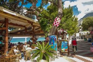 a street with a tree and people sitting at tables at Beachfront Rooms Ana in Tučepi