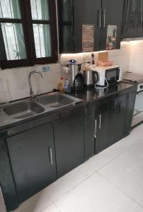 a kitchen with black cabinets and a sink at Passadeira Garden in São Tomé