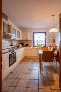 cocina con armarios blancos, mesa y ventana en Ferienhaus Olbernhau, en Olbernhau