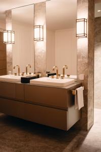 two sinks in a bathroom with two mirrors at MEWS House Zürich in Zürich