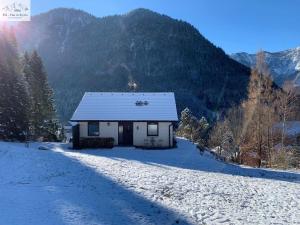 een klein huis in de sneeuw met bergen op de achtergrond bij Ferienhaus Kleinod in Bräuhof
