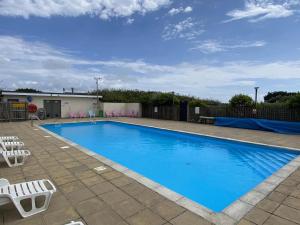 a large blue swimming pool with two lawn chairs at Lamorna in Penzance