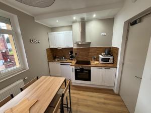 a kitchen with white cabinets and a wooden table at Les meublés de l Etoile in Eu