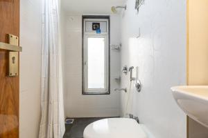 a white bathroom with a toilet and a window at Treat Homes Service Apartment in BKC Siddhant 401 in Mumbai +47 photos