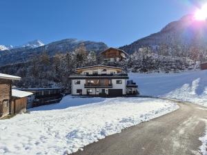 a house in the snow next to a road at Mountainsurf Apartments in Finkenberg