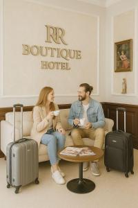 a man and woman sitting on a couch with luggage at RR Boutique Hotel in Yerevan